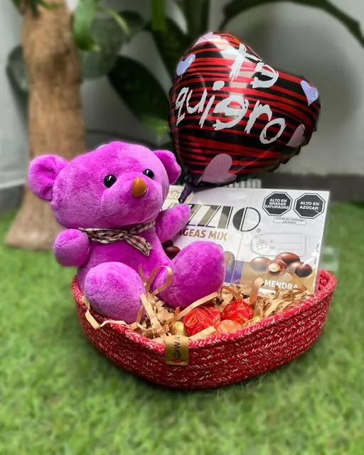 Detalle de regalo con cesta tejida, peluche y chocolates